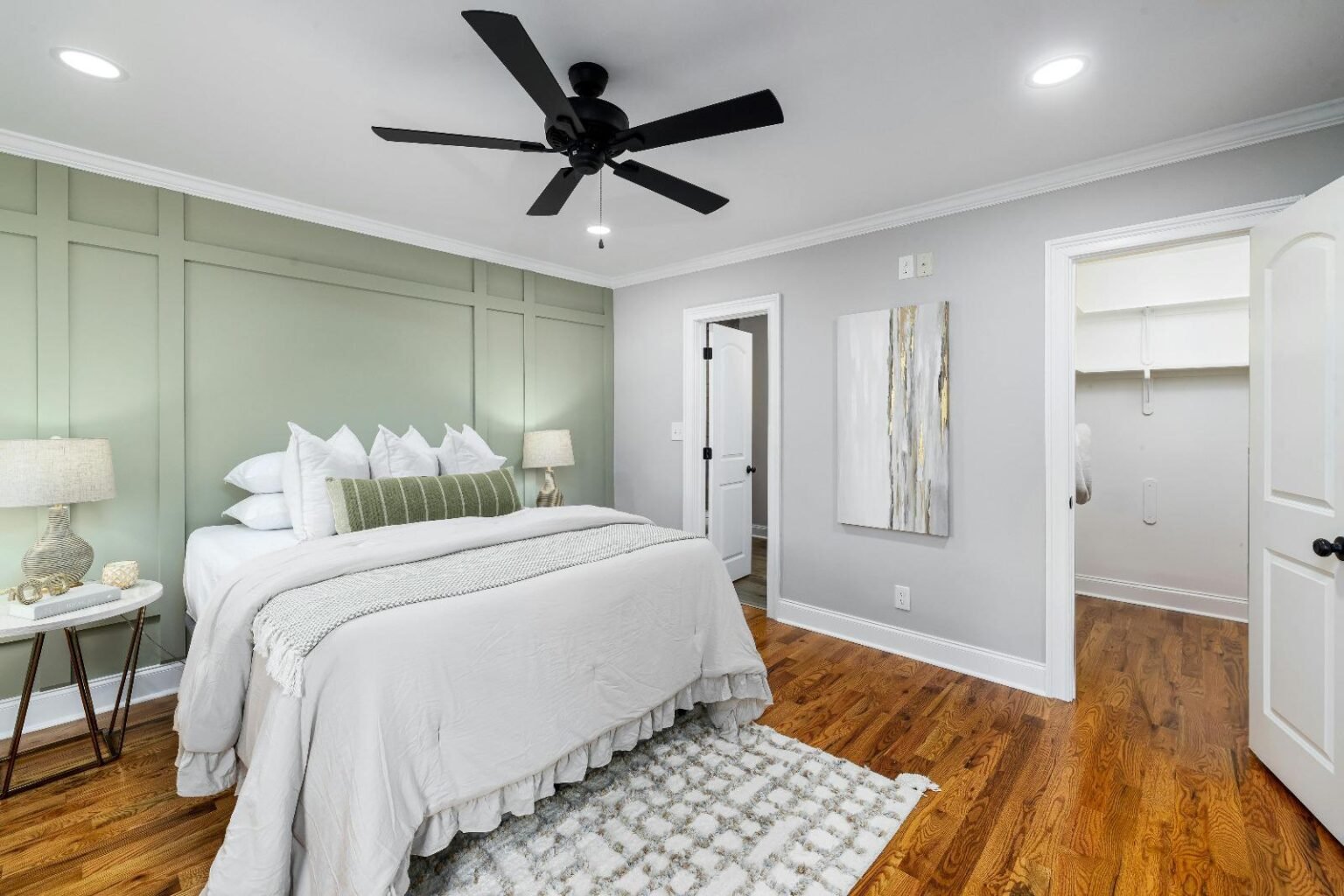Bedroom with a sage accent wall and hardwood floors.